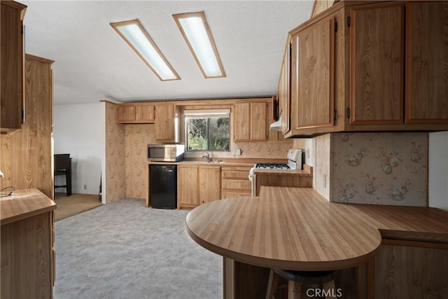 kitchen with sink, refrigerator, light carpet, kitchen peninsula, and white gas stove