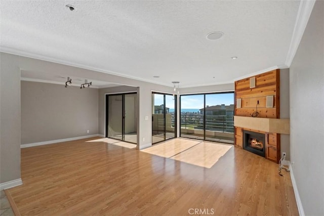 unfurnished living room featuring ornamental molding, a textured ceiling, and light hardwood / wood-style flooring