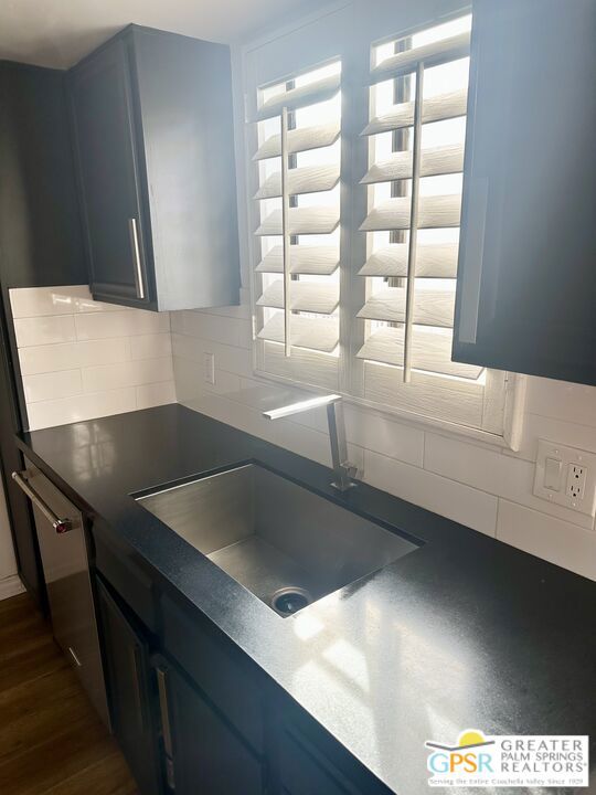 kitchen with dark wood-type flooring, blue cabinetry, sink, and decorative backsplash