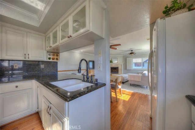 kitchen featuring a sink, white cabinetry, light wood-type flooring, freestanding refrigerator, and crown molding