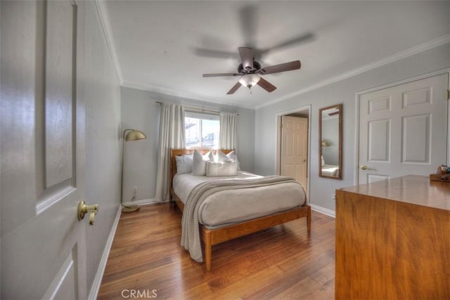 bedroom with ceiling fan, crown molding, baseboards, and wood finished floors