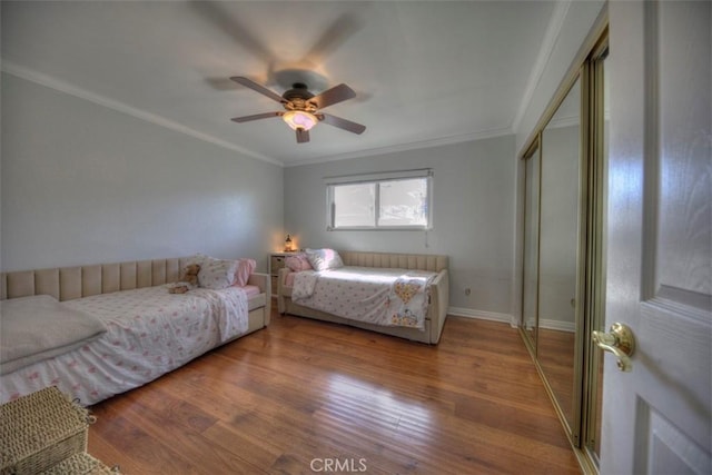 bedroom with ceiling fan, ornamental molding, a closet, and wood finished floors