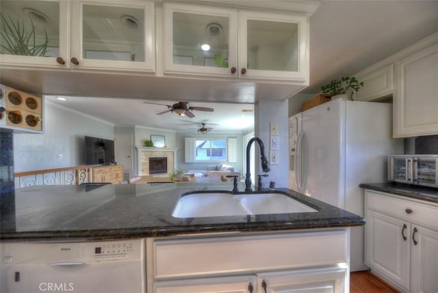 kitchen with ornamental molding, white cabinets, white dishwasher, a sink, and dark stone countertops