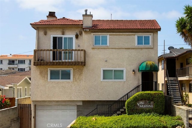 view of building exterior featuring a garage, fence, and stairs