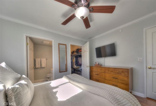 bedroom featuring ornamental molding, wood finished floors, a spacious closet, and ensuite bathroom