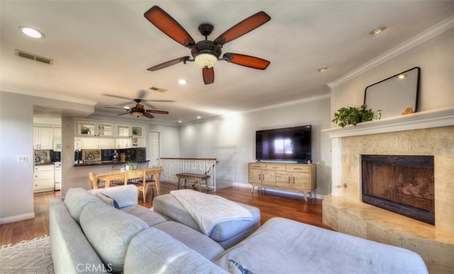 living area featuring ornamental molding, visible vents, a premium fireplace, and wood finished floors