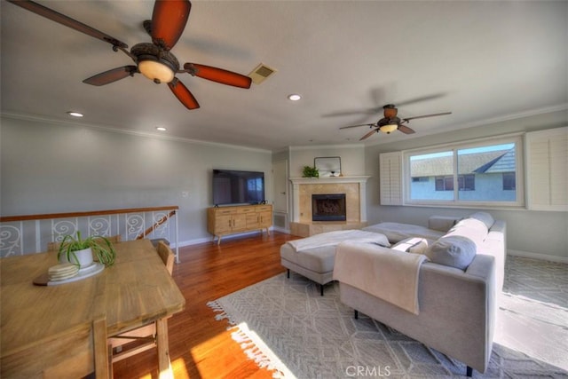 living room with ornamental molding, visible vents, and wood finished floors