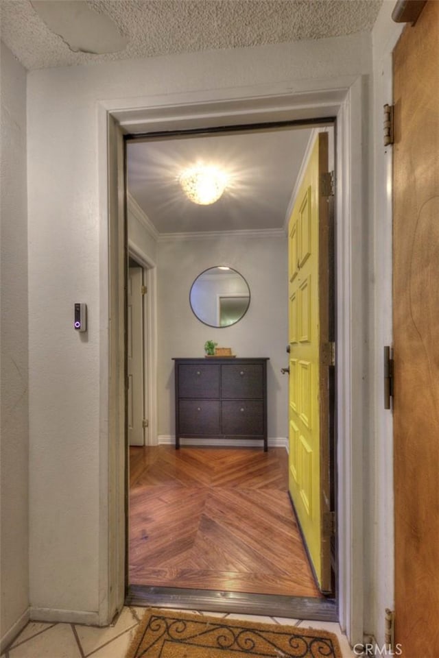 corridor featuring a textured ceiling, ornamental molding, and baseboards