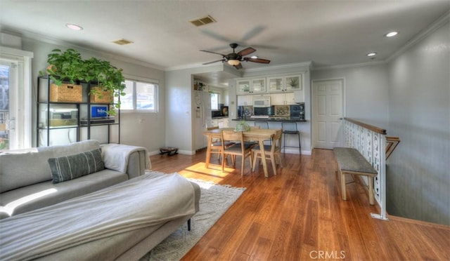 living room with visible vents, crown molding, baseboards, and wood finished floors