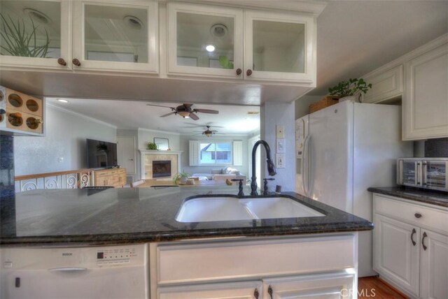 kitchen with sink, dark stone countertops, ornamental molding, white dishwasher, and white cabinets