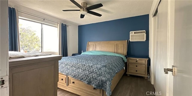 bedroom with ceiling fan, dark hardwood / wood-style floors, a wall mounted AC, and a textured ceiling