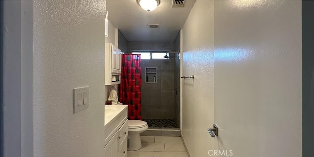 bathroom with vanity, a tile shower, tile patterned floors, and toilet