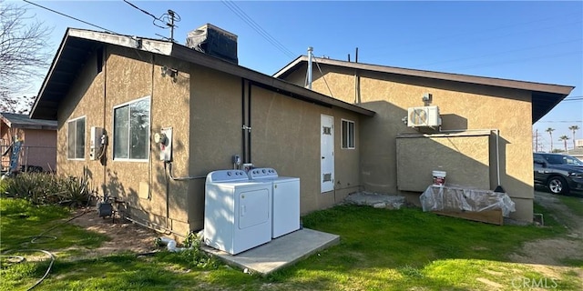 back of property featuring washing machine and dryer and a yard