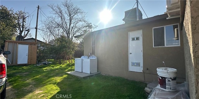 view of side of home featuring separate washer and dryer, a lawn, and a shed