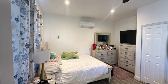 bedroom with wood-type flooring, an AC wall unit, and ceiling fan