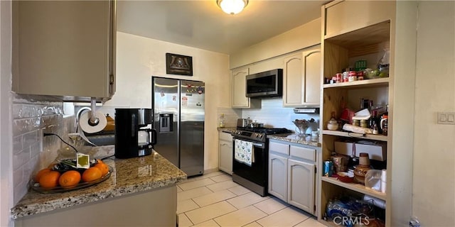 kitchen featuring light stone counters, stainless steel appliances, light tile patterned floors, and backsplash