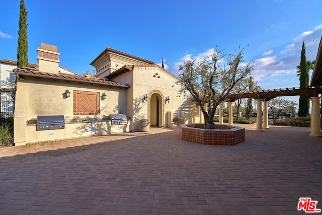 exterior space featuring an outdoor kitchen, a pergola, and a patio area