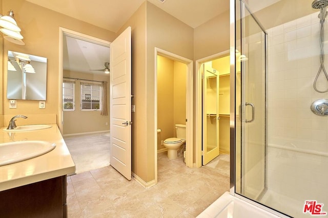 bathroom featuring ceiling fan, vanity, toilet, and a shower with door