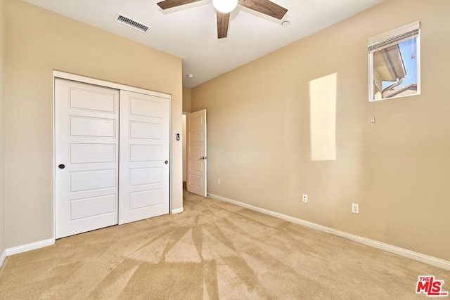 unfurnished bedroom featuring light colored carpet, a closet, and ceiling fan