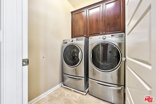 clothes washing area with washer and clothes dryer and cabinets