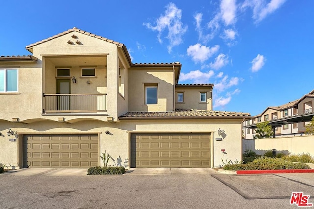 mediterranean / spanish-style home featuring a garage and a balcony