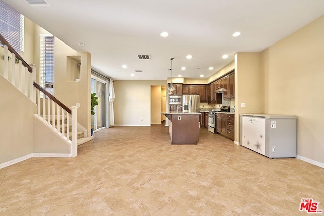 kitchen with appliances with stainless steel finishes, decorative light fixtures, a breakfast bar area, a center island, and light stone counters