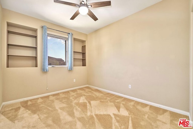 empty room with carpet floors, built in features, and ceiling fan