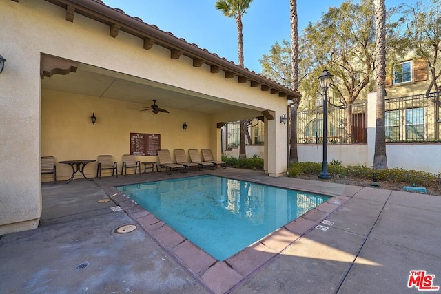 view of swimming pool featuring ceiling fan and a patio