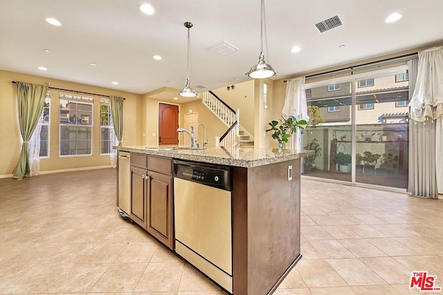 kitchen featuring pendant lighting, an island with sink, sink, stainless steel dishwasher, and light stone countertops