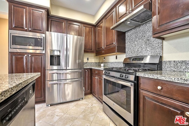 kitchen featuring light stone counters, light tile patterned floors, dark brown cabinetry, and appliances with stainless steel finishes