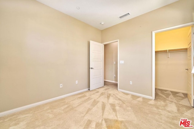 unfurnished bedroom featuring light colored carpet, a spacious closet, and a closet