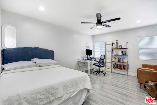 bedroom featuring ceiling fan, multiple windows, and light hardwood / wood-style flooring