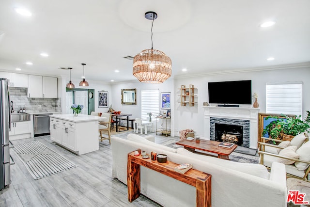 living room with a tiled fireplace, ornamental molding, and light hardwood / wood-style floors