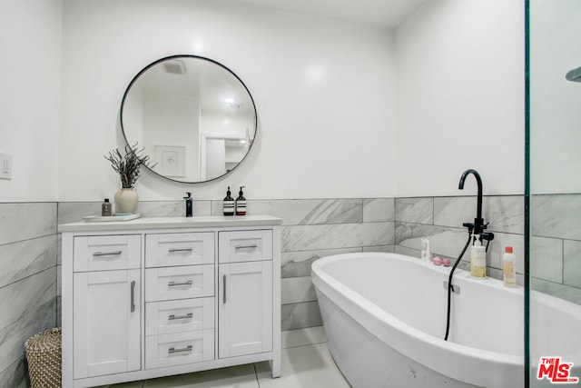 bathroom with vanity, a tub, and tile walls