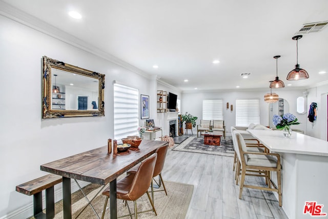 dining room with crown molding and light hardwood / wood-style floors