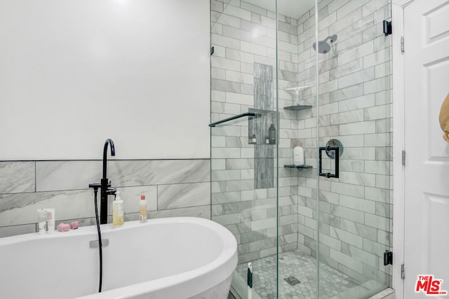 bathroom with plus walk in shower, sink, and tile walls