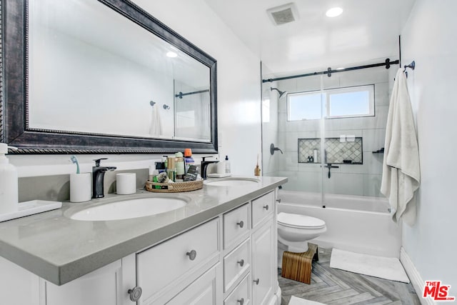 full bathroom with parquet floors, vanity, bath / shower combo with glass door, and toilet