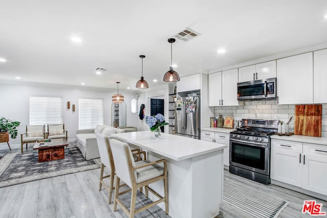 kitchen featuring pendant lighting, a breakfast bar, stainless steel appliances, a center island, and white cabinets