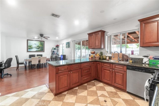 kitchen with gas stove, sink, dark stone countertops, stainless steel dishwasher, and kitchen peninsula