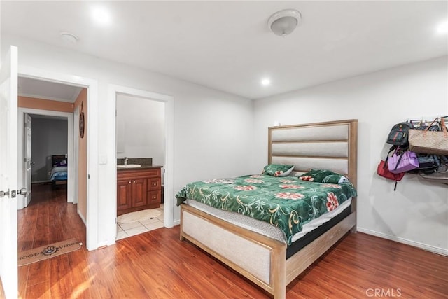 bedroom featuring connected bathroom, sink, and hardwood / wood-style floors