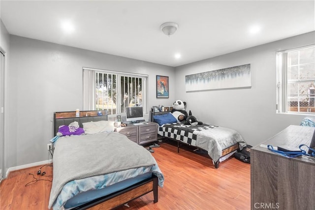 bedroom with multiple windows and light hardwood / wood-style flooring