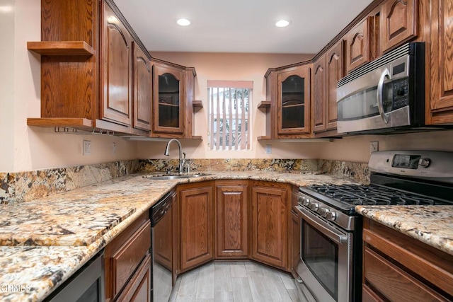 kitchen featuring stainless steel appliances, light stone countertops, and sink