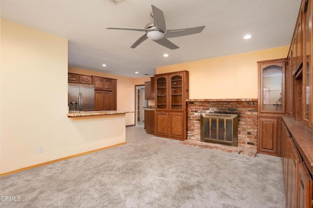 unfurnished living room with ceiling fan, light carpet, and a fireplace