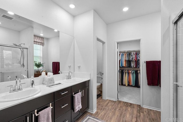 bathroom with an enclosed shower, vanity, wood-type flooring, and toilet