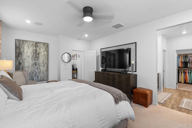 bedroom featuring a spacious closet, light hardwood / wood-style floors, a closet, and ceiling fan