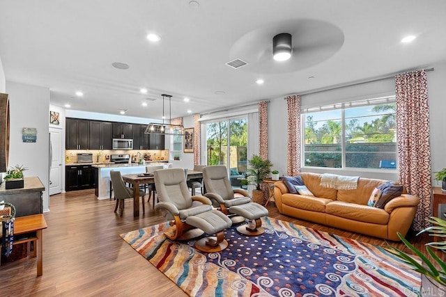 living room featuring a ceiling fan, visible vents, wood finished floors, and recessed lighting