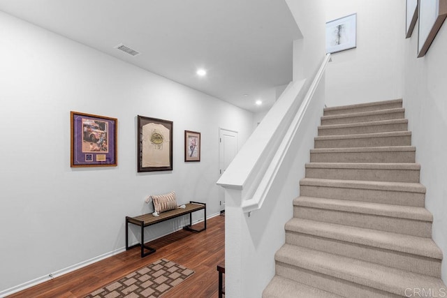 stairway with baseboards, wood finished floors, visible vents, and recessed lighting