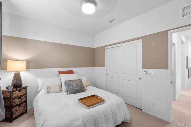 bedroom featuring a closet, visible vents, and light carpet