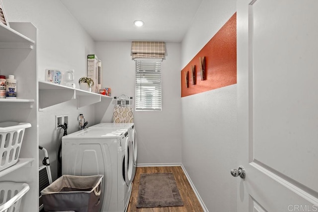 clothes washing area with washer and dryer, laundry area, baseboards, and wood finished floors