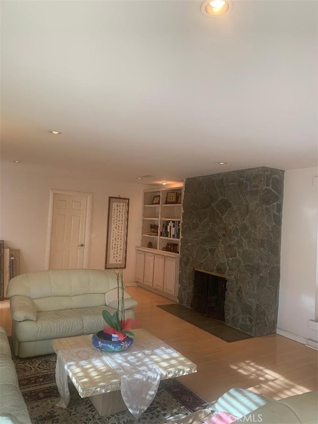 living room with wood-type flooring and a stone fireplace